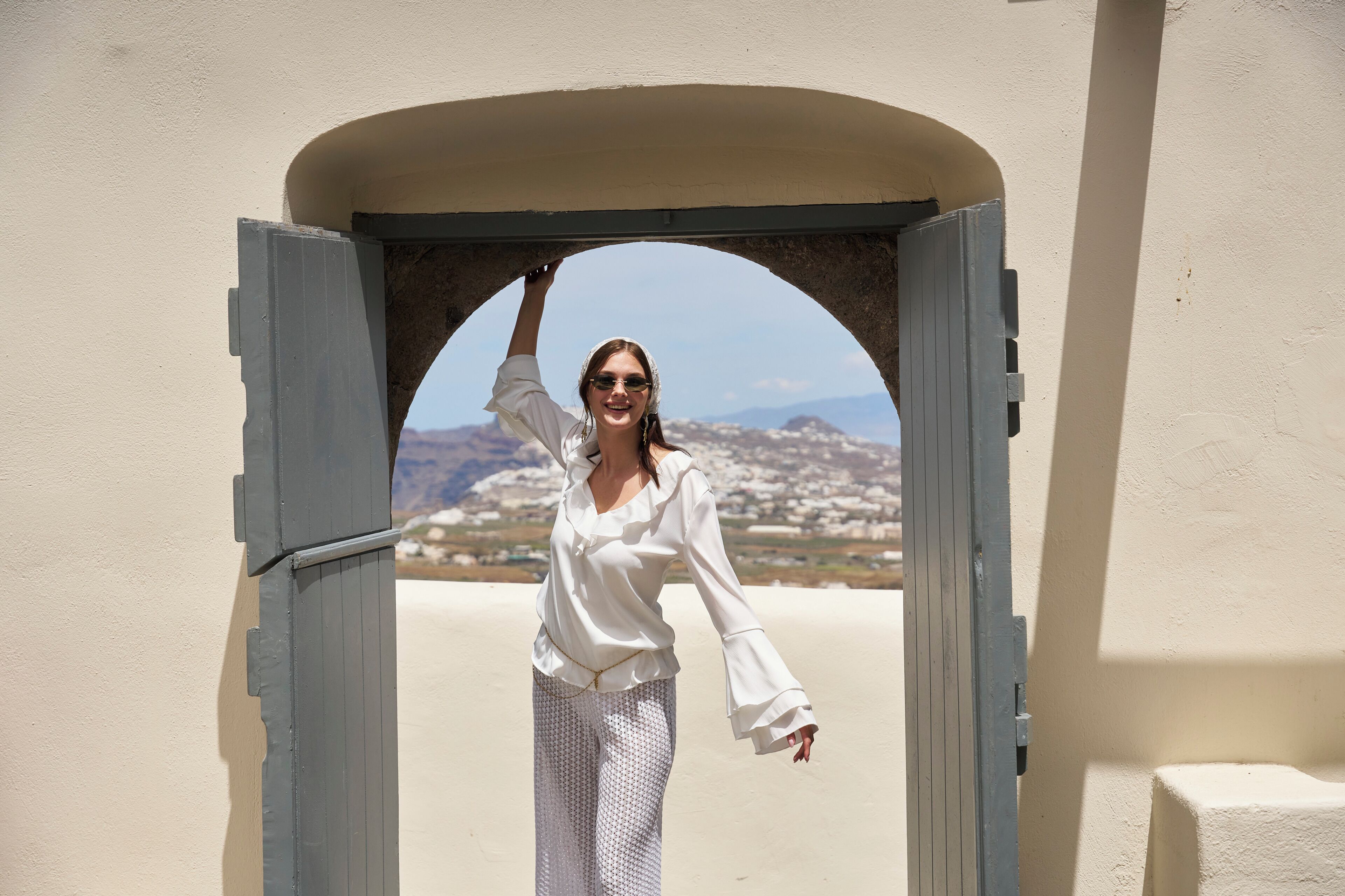 Una persona de pie en un arco con vistas a un paisaje lejano.
