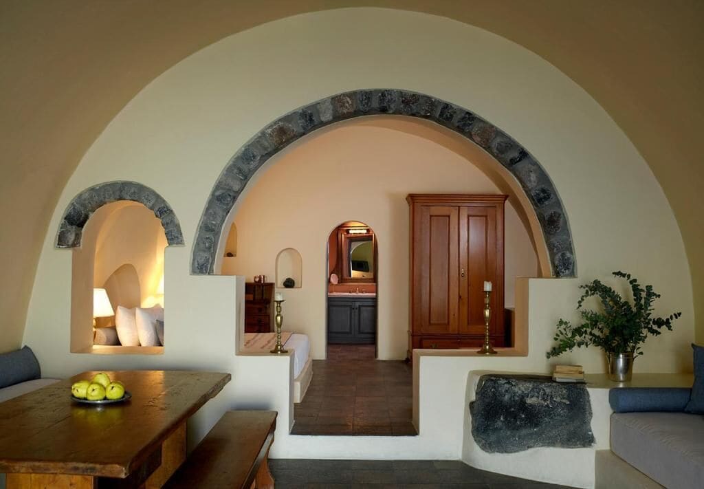 An interior with a stone archway leading to a kitchen and dining area.