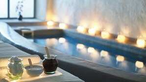 A spa area with a pool, candles, and jars of honey and syrup. - Zannos Melathron Hotel by Omilos Hotels (Santorini)