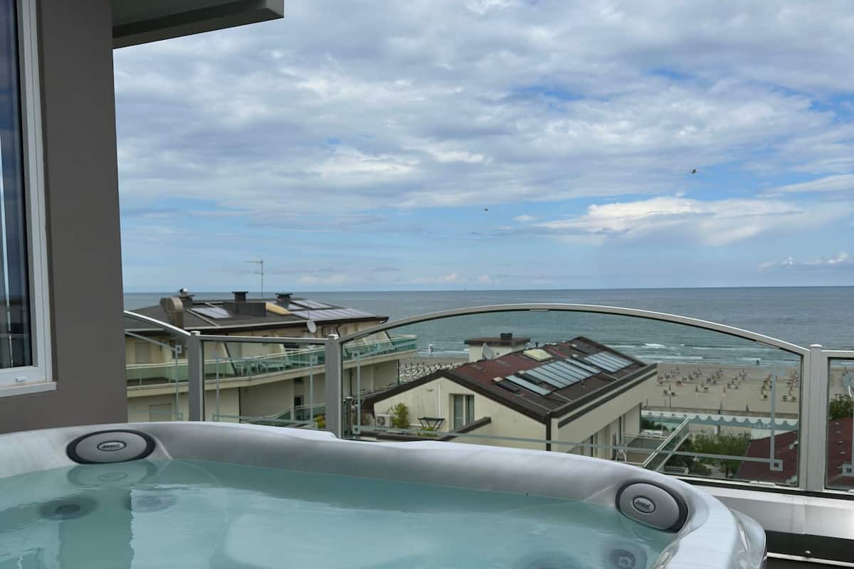 A hot tub with a view of the ocean and buildings in the background.