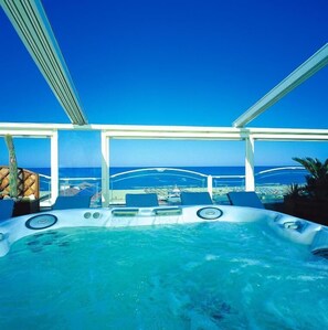 A hot tub with a view of the ocean, surrounded by lounge chairs and a glass ceiling. - Hotel Alexander (Cervia)