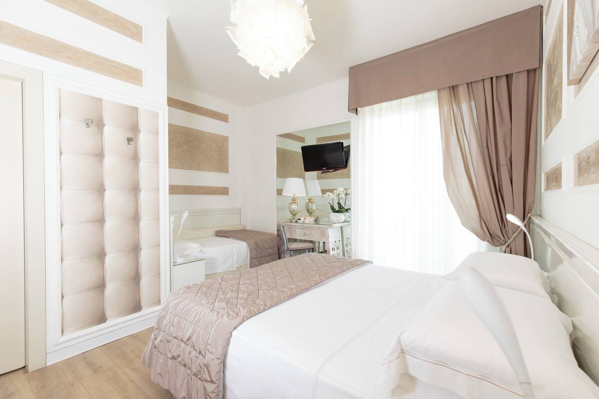 A hotel room with a bed, a desk, a chair, a television, and a wardrobe.