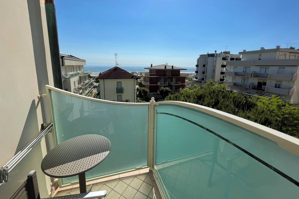 A balcony with a glass barrier, a small round table, and a chair.