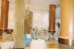 Un vestíbulo moderno con zona de estar, mostrador de recepción y columnas decorativas.