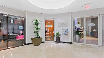 A hotel lobby with a modern design, featuring a large potted plant, glass display cases, and a sign for the pool and beach club.