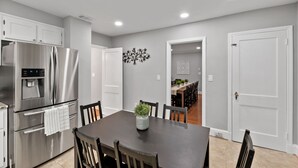 A modern kitchen with stainless steel appliances, a dining table with chairs, and a decorative wall piece.