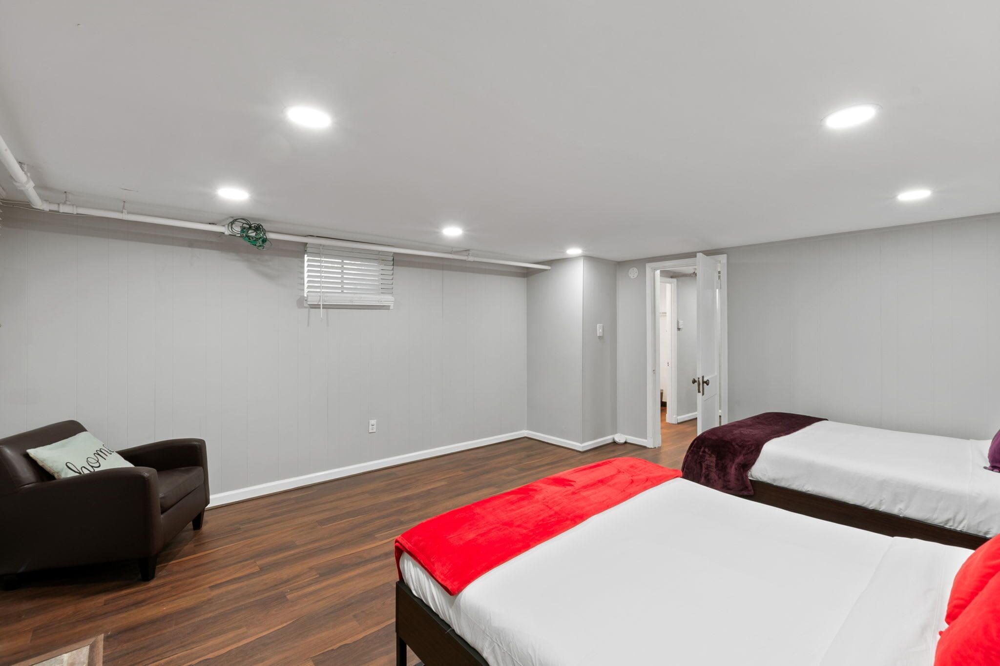 Ein Zimmer mit zwei Betten, einem Sofa und einem Fenster mit Jalousien.