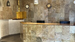 En receptionsdisk af marmor, gulv med skakmønster og et vægur.