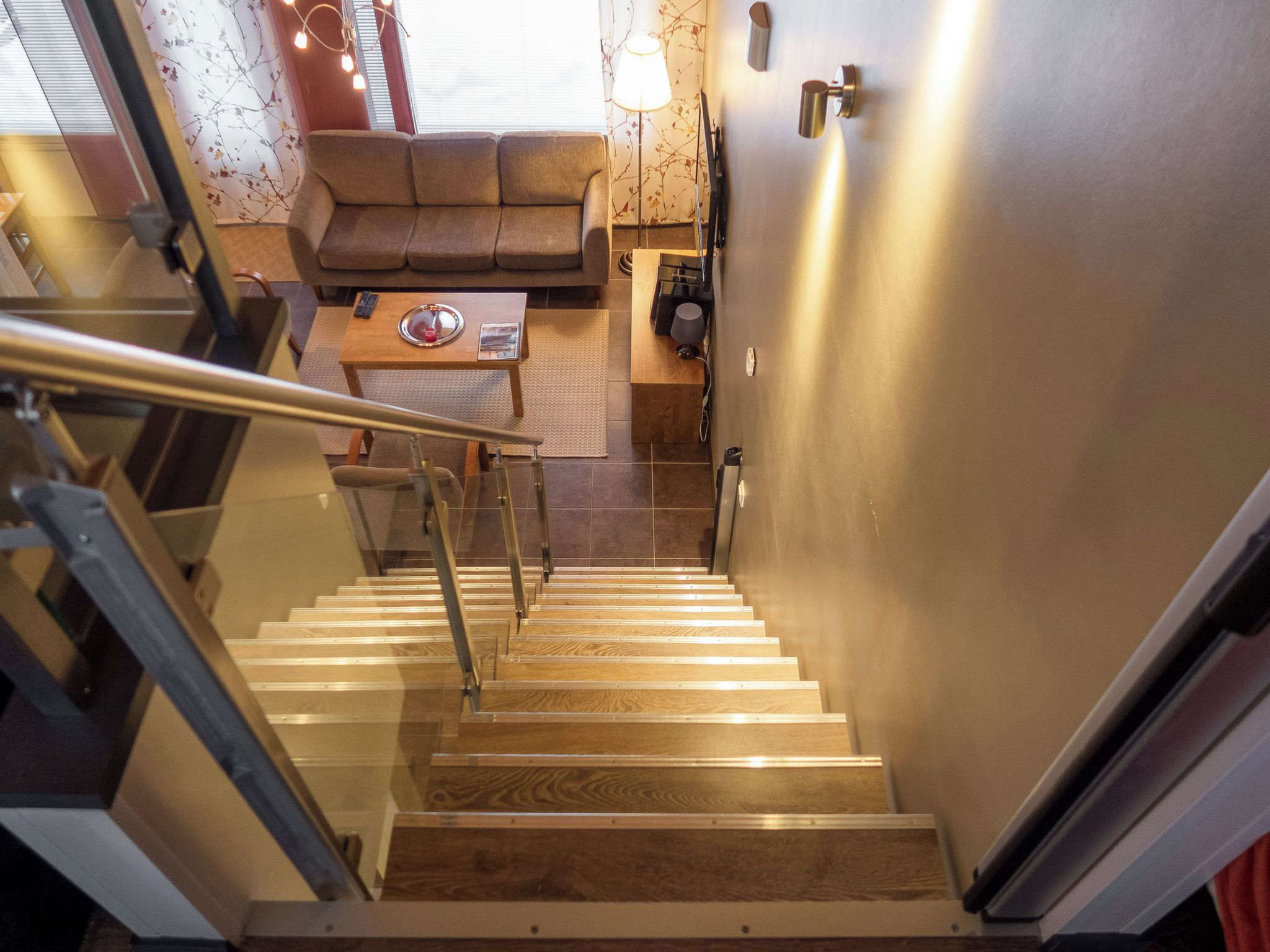 A staircase leading to a living area with a sofa, a coffee table, and a lamp.