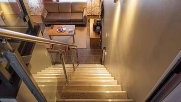 A staircase leading to a living area with a sofa, a coffee table, and a lamp.