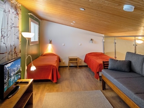 A room with two beds, a sofa, a TV, and a lamp.