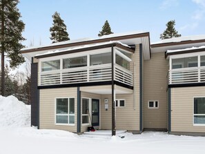 Un bâtiment moderne à deux étages, doté d’un balcon à l’étage supérieur, de grandes fenêtres et d’un sol recouvert de neige.