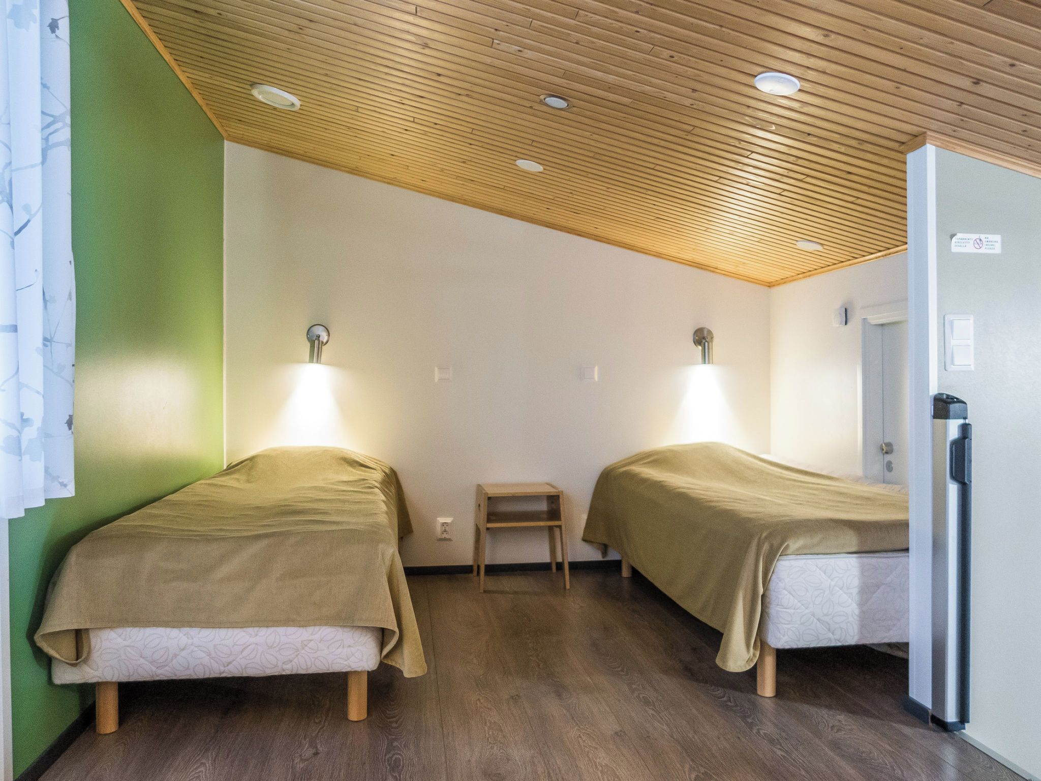 Une chambre avec deux lits, une petite table et un réfrigérateur.
