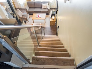 Una escalera que lleva a una sala de estar con un sofá, una mesa y una lámpara.