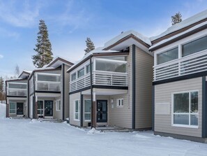 Una hilera de edificios residenciales modernos de varios pisos con balcones, en un paisaje nevado.