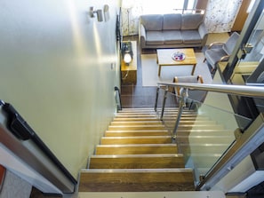 Una escalera con escalones de madera y barandillas de metal que conduce a una sala de estar con un sofá y una mesa.