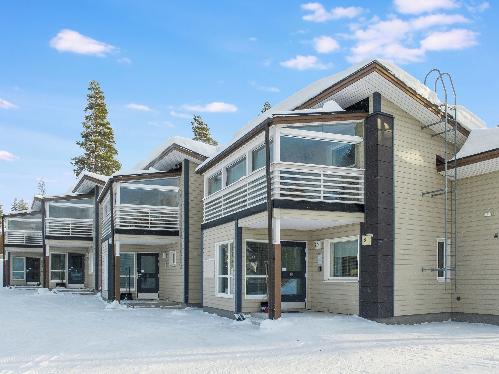 A row of modern multi-story buildings with large windows and balconies, surrounded by snow.