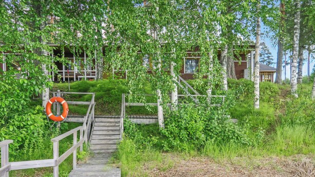 A wooden pathway leading to a building with a lifebuoy on the left.