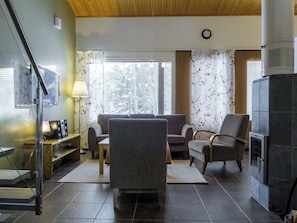 Un salon avec un canapé, des fauteuils, un téléviseur et une cheminée.