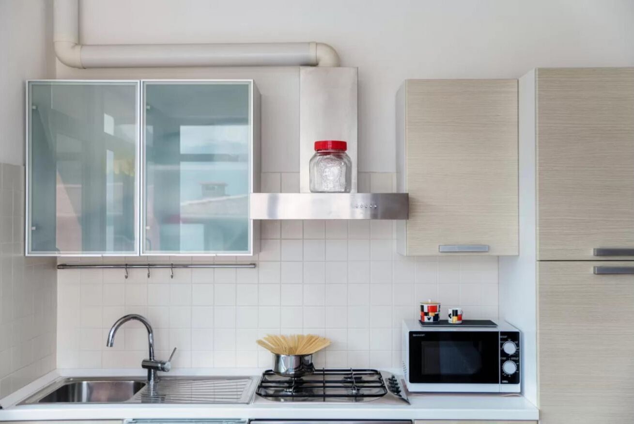 Una cocina moderna con estufa a gas, microondas, lavaplatos y un mueble con un tarro sobre la encimera.