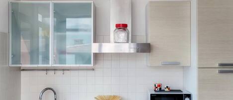 Una cocina moderna con estufa a gas, microondas, lavaplatos y un mueble con un tarro sobre la encimera.