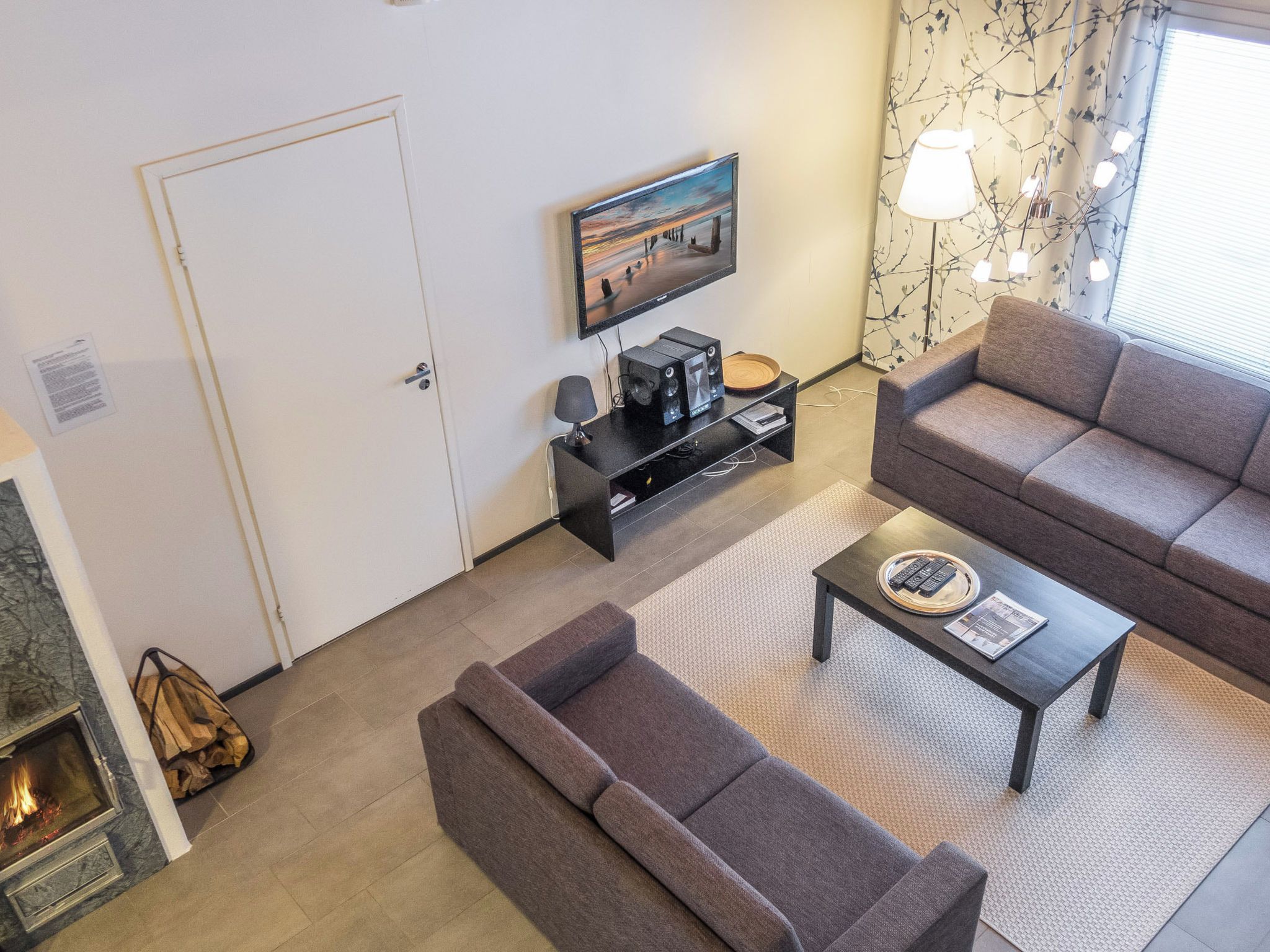 Un salon avec un canapé, une table basse, un téléviseur et une cheminée.