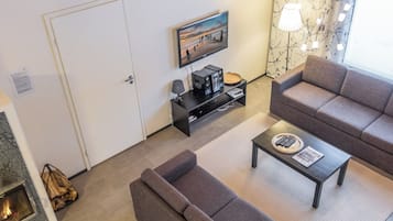 A living room with a sofa, a coffee table, a TV, and a fireplace.