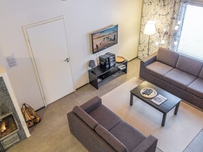 Una sala de estar con sofá, mesa de centro, televisor y chimenea.