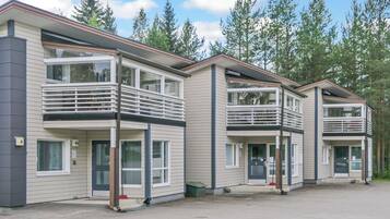 A row of modern multi-story buildings with balconies, large windows, and a parking area.