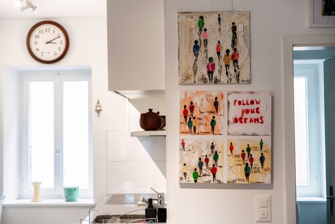 Una cucina con mobili bianchi, un orologio e opere d'arte alle pareti.