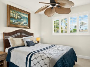 Ein Schlafzimmer mit Bett, einem Gemälde, einem Fenster mit Blick und einem Deckenventilator.