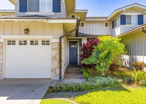 A residential house with a garage, a front door, and a well-maintained garden with various plants.