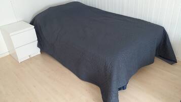 Une chambre à coucher avec un lit, une table de chevet blanche et un plancher en bois.