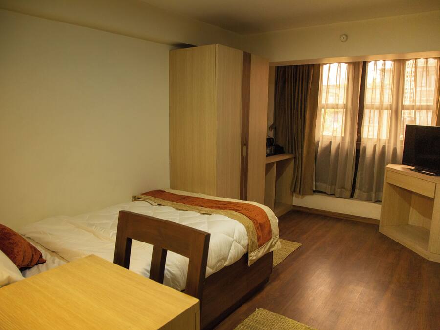 Een slaapkamer met een bed, bureau, televisie en kledingkast.