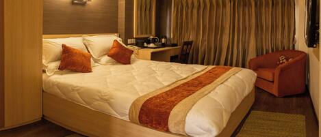 Una habitación de hotel con una cama grande, un escritorio, una silla y un televisor.