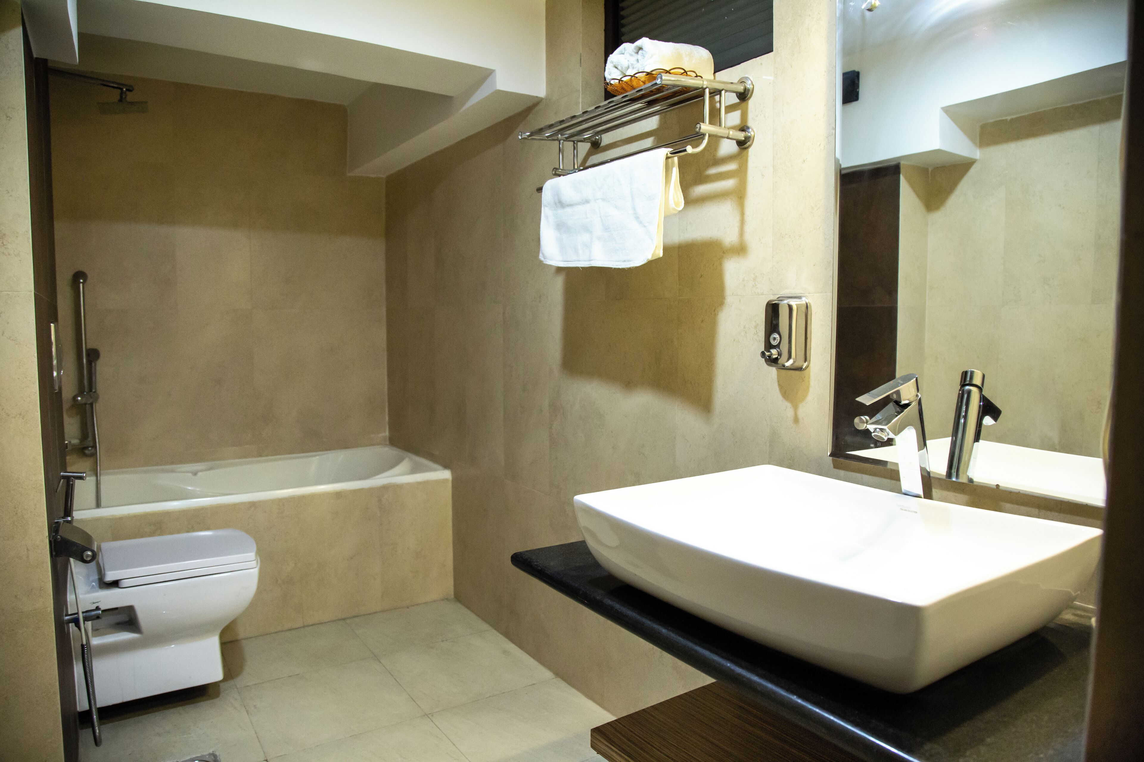 A modern bathroom with a bathtub, toilet, and a large sink with a mirror.