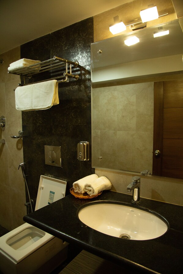 A bathroom with a black countertop, a white sink, a towel rack, and a mirror.