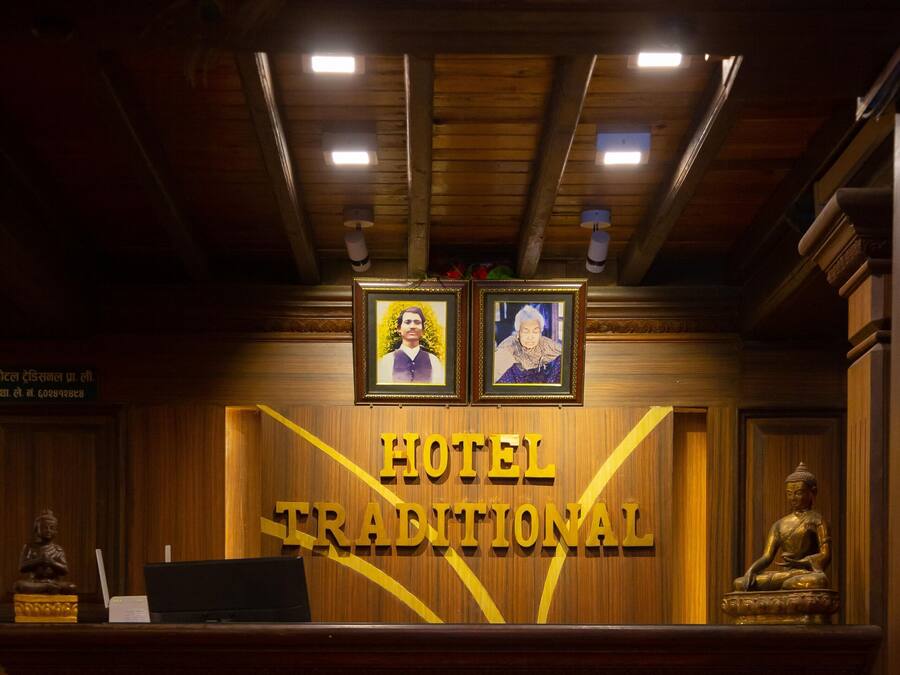 A reception desk with a sign reading "HOTEL TRADITIONAL" and two framed pictures above it.