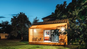 A small wooden cabin with a glass door leading to an interior with a sofa and a dining area. - Ostravinka - Boutique Apartment (Ostrava)