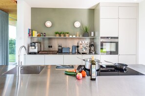 A modern kitchen with a central island, stainless steel appliances, and a variety of kitchen tools and fresh produce.
