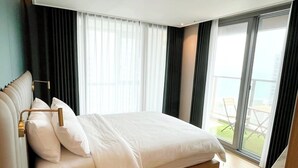 Una habitación de hotel moderna con una cama grande, vistas al exterior y un balcón.