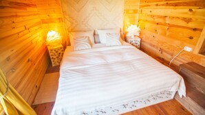 Une chambre à coucher dans une cabane en bois, avec un lit, des oreillers et une table de chevet.