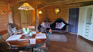 L’intérieur d’une cabane en bois, avec une table à manger, des chaises, un canapé et un buffet.