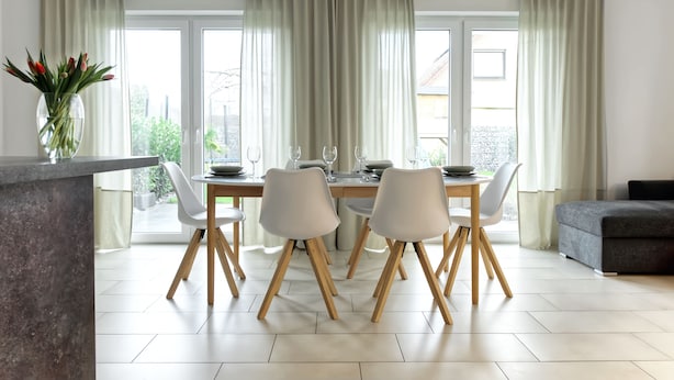 Zona pranzo moderna con tavolo apparecchiato per quattro, circondato da sedie con gambe in legno.