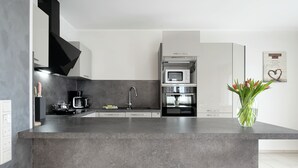 Una cucina moderna con una grande isola, elettrodomestici integrati e un vaso con fiori.
