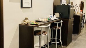 A modern kitchen with a bar area, including a coffee machine, a clock, and framed notices on the wall. - Beautiful Colosseum Roma (Rome)