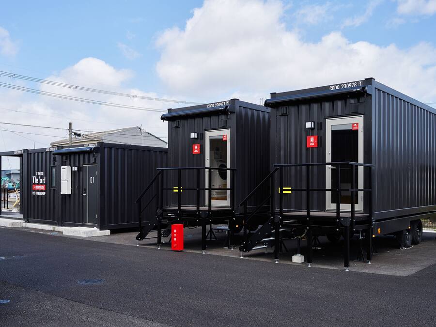 Two black shipping containers with external stairs, a fire hydrant, and a red mailbox.