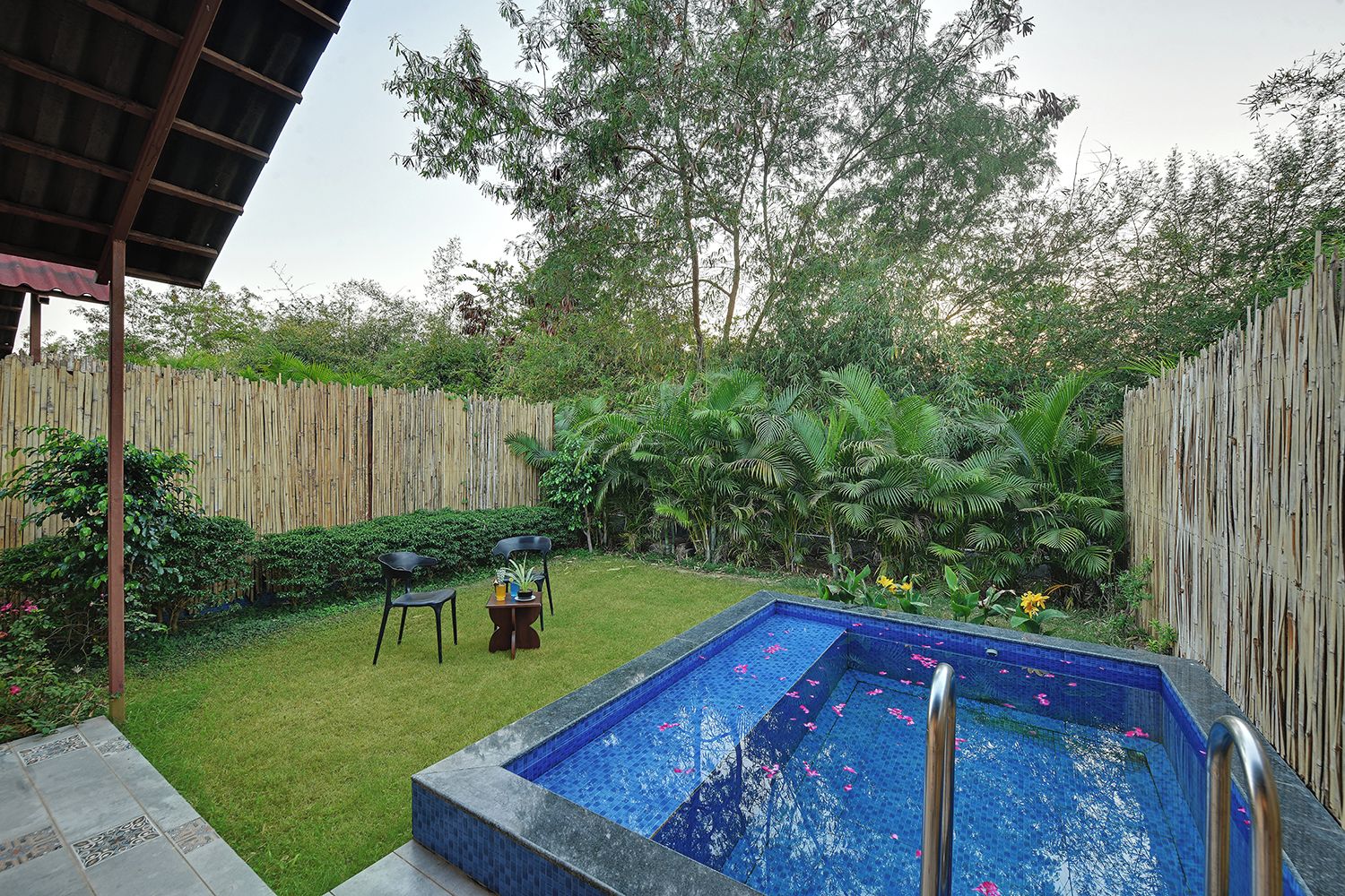 Une piscine rectangulaire bordée de carreaux, entourée d’une clôture en bois, d’une pelouse et de quelques plantes.