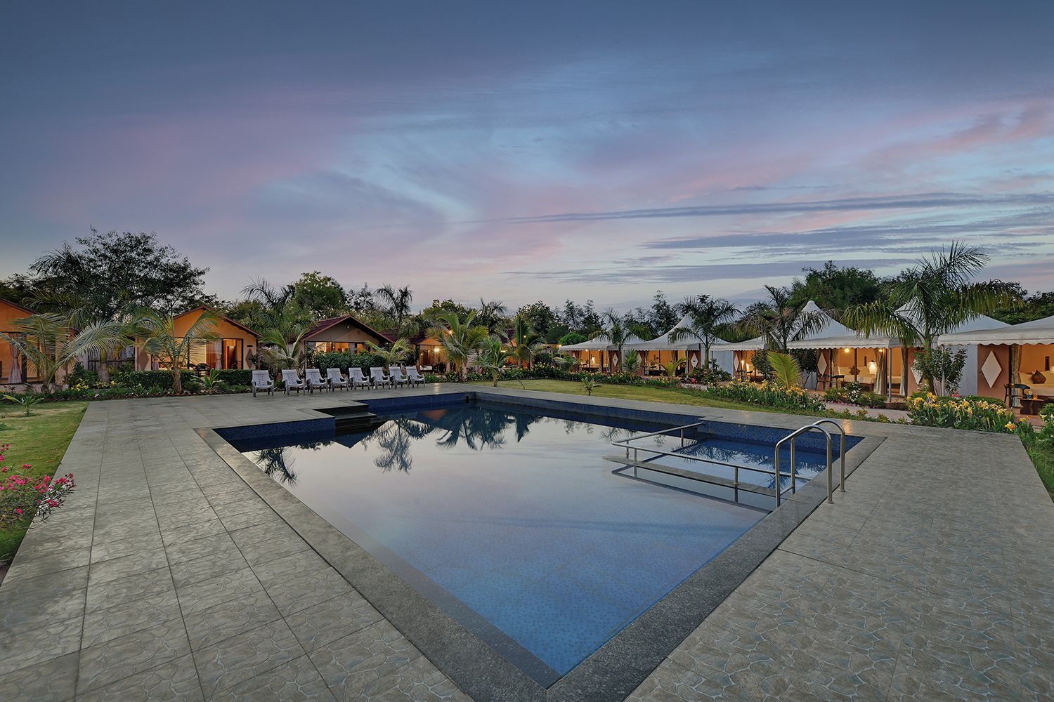Un resort con piscina, sillones de descanso y bungalós sobre el agua.