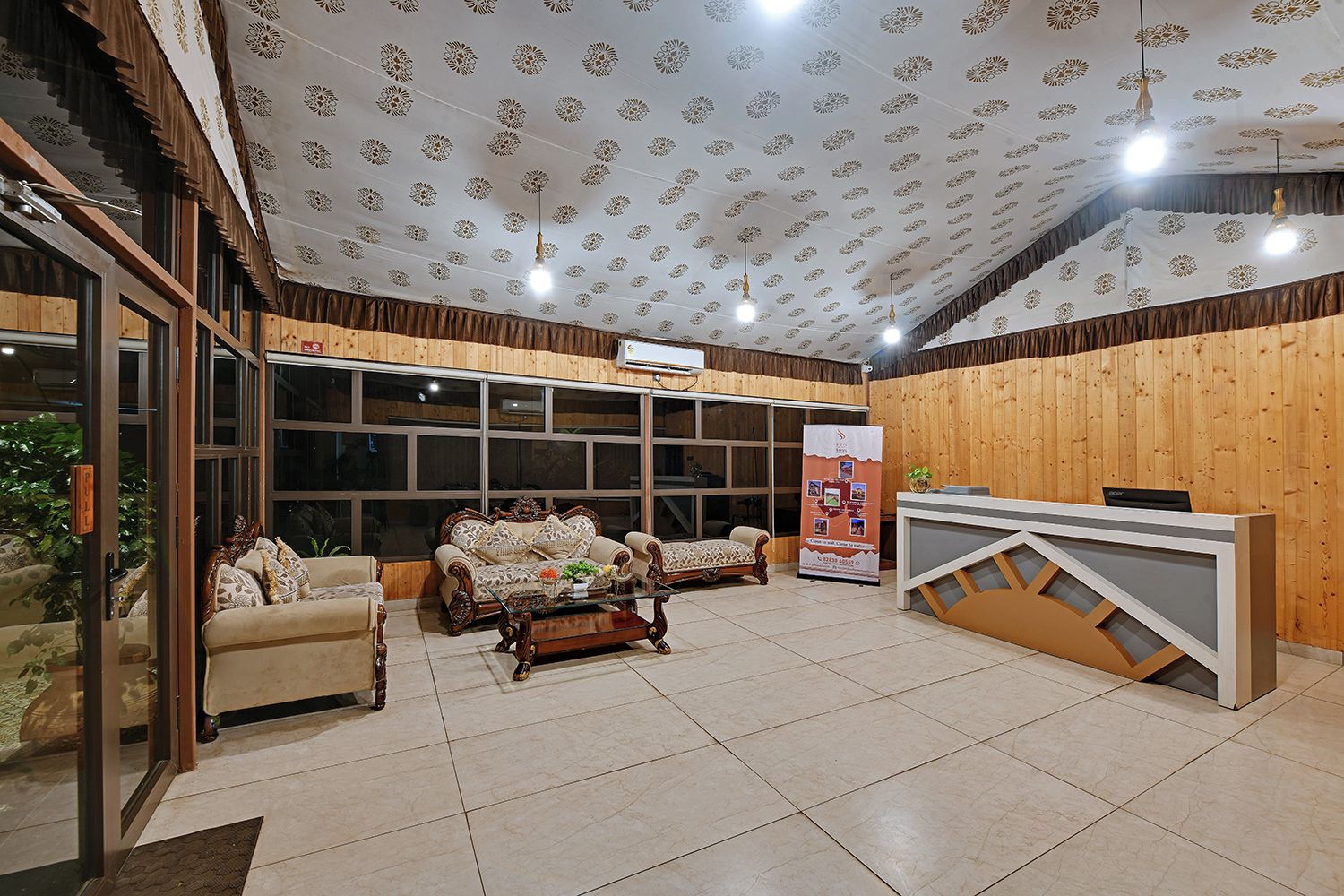 A reception area with a reception desk, two sofas, a coffee table, and a patterned ceiling.